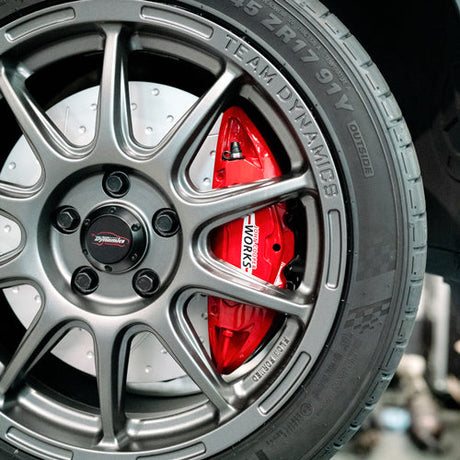 Red John Cooper Works brakes showing behind team dynamics wheels on an F56 MINI